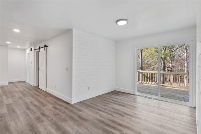 unfurnished room featuring a barn door and light hardwood / wood-style floors