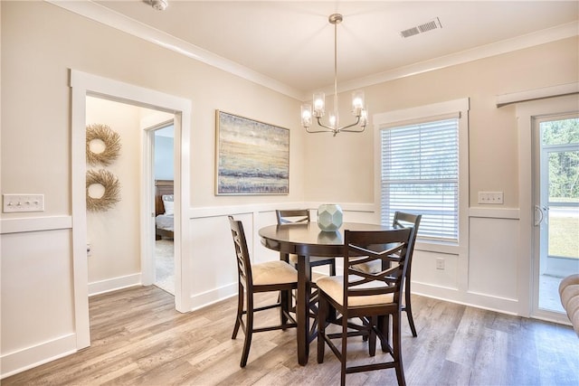 dining area featuring crown molding, a chandelier, and light hardwood / wood-style floors