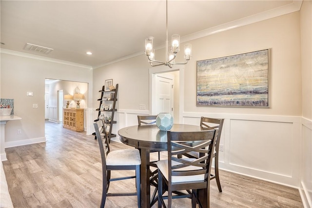 dining room with ornamental molding, a notable chandelier, and light hardwood / wood-style flooring