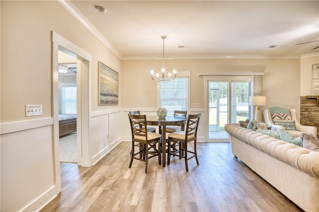 dining area with ceiling fan with notable chandelier, ornamental molding, and light hardwood / wood-style floors