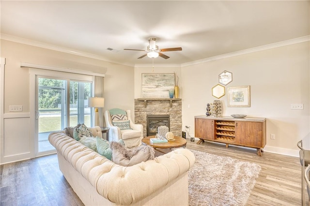 living room with a stone fireplace, wood-type flooring, ornamental molding, and ceiling fan