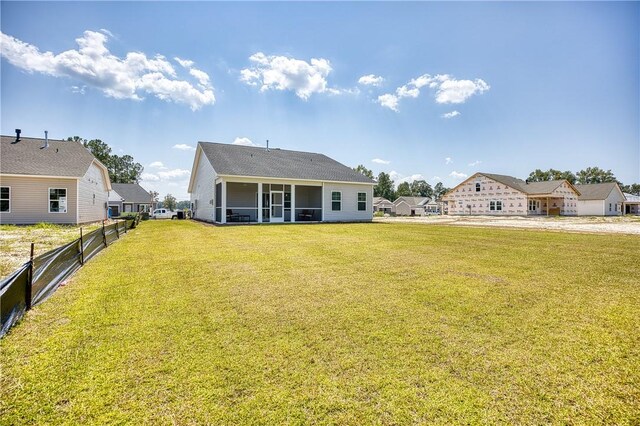 back of property with a sunroom and a lawn