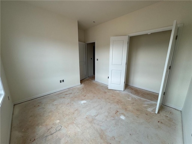 unfurnished bedroom featuring baseboards and unfinished concrete flooring