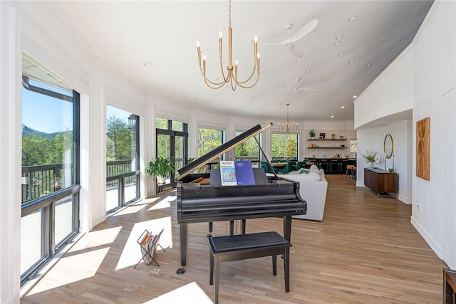 miscellaneous room featuring ceiling fan with notable chandelier, light hardwood / wood-style floors, and high vaulted ceiling