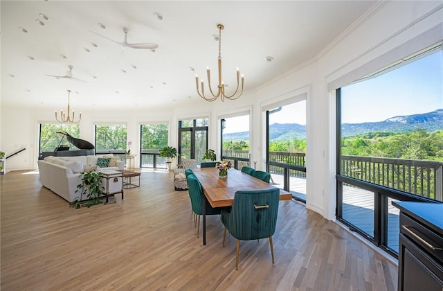 dining area featuring a mountain view, ornamental molding, ceiling fan with notable chandelier, and light hardwood / wood-style flooring