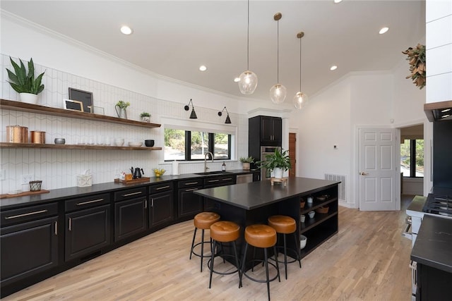 kitchen featuring sink, a kitchen breakfast bar, light hardwood / wood-style flooring, a kitchen island, and ornamental molding