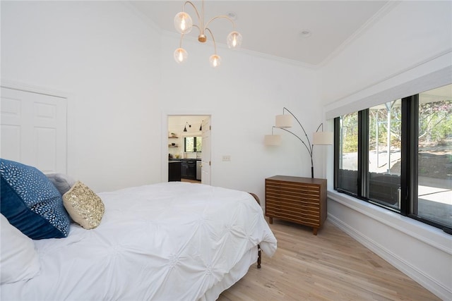 bedroom with light hardwood / wood-style flooring, an inviting chandelier, a high ceiling, and ornamental molding