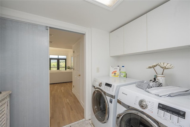 laundry room with cabinets, light hardwood / wood-style floors, and washer and clothes dryer