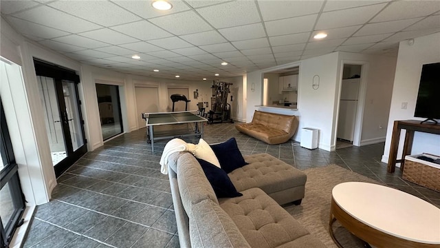 living room with french doors, a paneled ceiling, and dark tile patterned floors