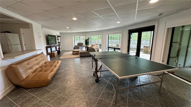 playroom featuring french doors, a paneled ceiling, dark tile patterned flooring, and a healthy amount of sunlight