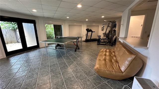 rec room featuring a paneled ceiling, dark tile patterned floors, and french doors