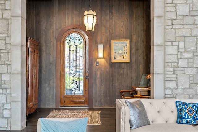 foyer with wood walls, dark wood-type flooring, and a high ceiling