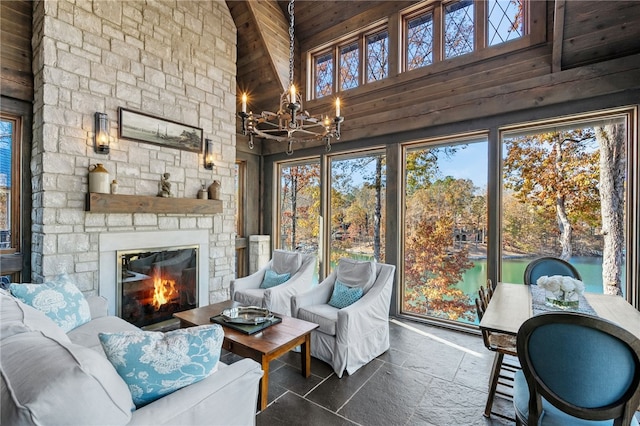 sunroom / solarium with vaulted ceiling with beams, a fireplace, and a chandelier