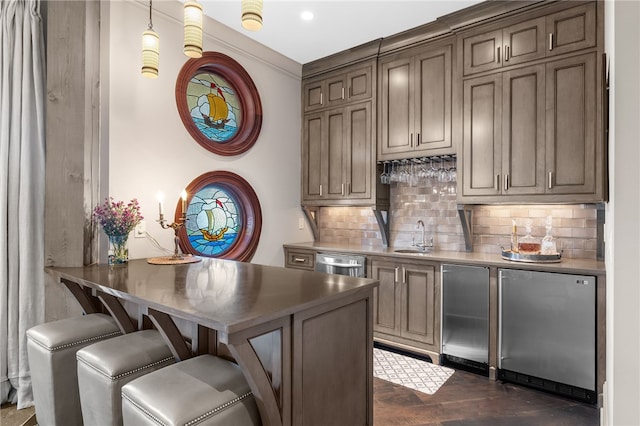 bar with sink, dark wood-type flooring, backsplash, pendant lighting, and appliances with stainless steel finishes