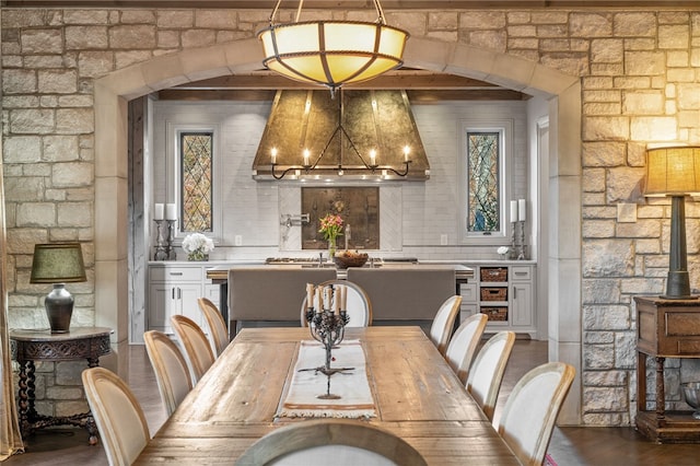 dining room with a chandelier, arched walkways, and wood finished floors