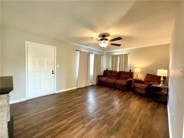 living room with a fireplace, a textured ceiling, dark hardwood / wood-style flooring, and ceiling fan