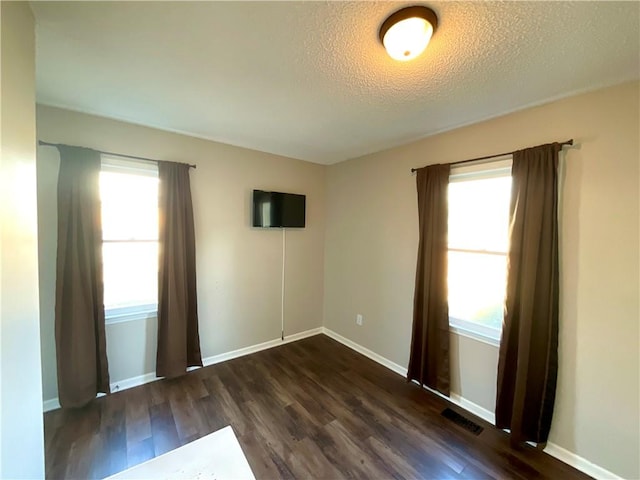 empty room featuring a textured ceiling and dark hardwood / wood-style floors