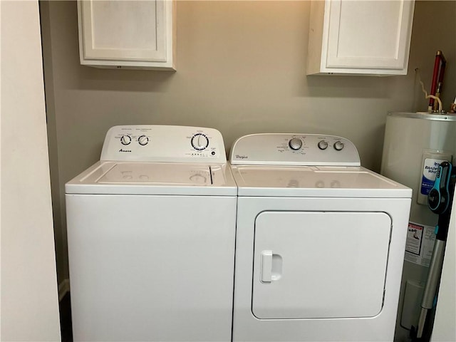 washroom featuring washing machine and clothes dryer, electric water heater, and cabinets