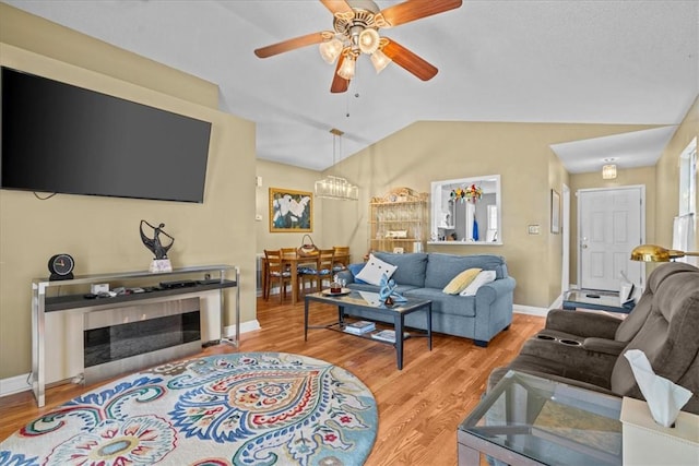 living room with ceiling fan, light hardwood / wood-style flooring, and vaulted ceiling