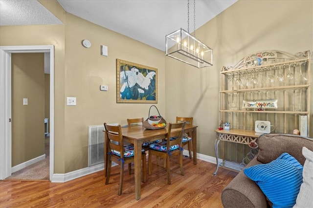 dining room with hardwood / wood-style flooring, lofted ceiling, and an inviting chandelier