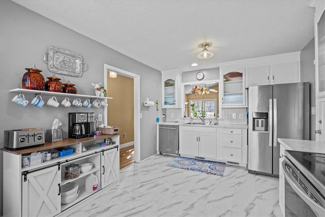 kitchen featuring backsplash, white cabinets, sink, a textured ceiling, and appliances with stainless steel finishes