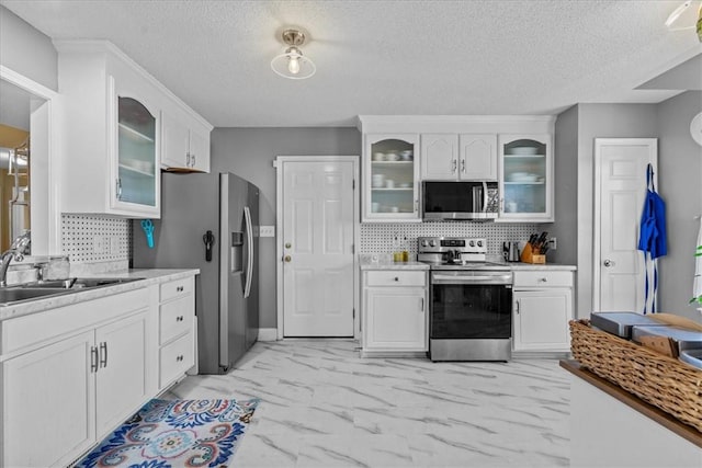 kitchen with backsplash, white cabinets, stainless steel appliances, and a textured ceiling