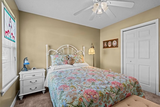 bedroom with ceiling fan, dark carpet, a textured ceiling, and a closet