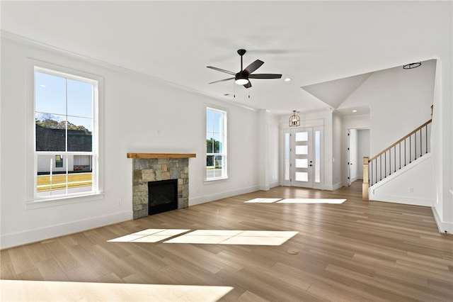 unfurnished living room with ceiling fan with notable chandelier, light hardwood / wood-style floors, and a fireplace