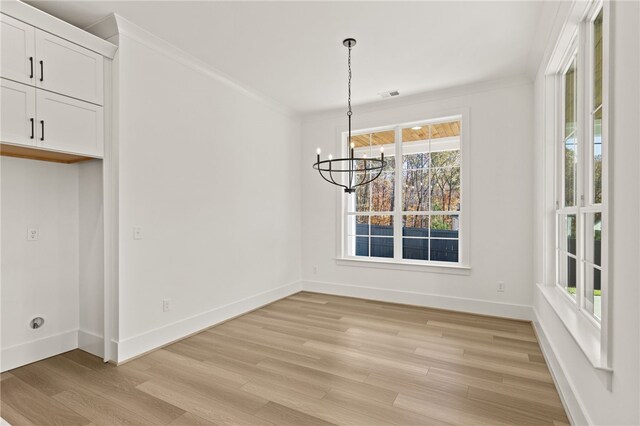 unfurnished dining area featuring a notable chandelier, light hardwood / wood-style floors, and crown molding