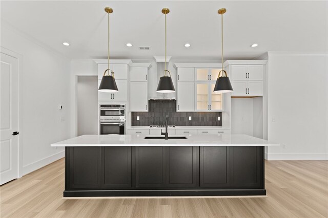kitchen featuring white cabinetry, an island with sink, and light hardwood / wood-style floors