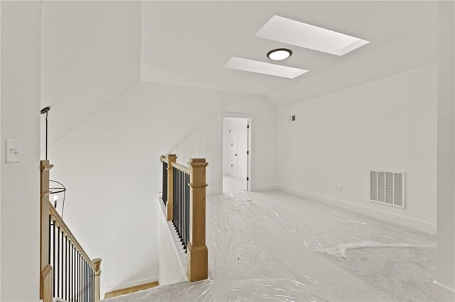 interior space featuring light colored carpet and lofted ceiling with skylight