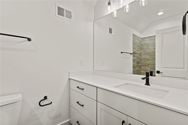 bathroom with vanity, toilet, and lofted ceiling