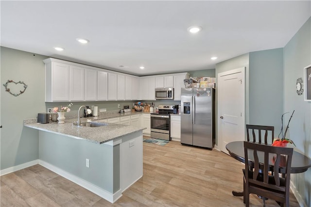 kitchen with white cabinetry, sink, appliances with stainless steel finishes, and light hardwood / wood-style flooring