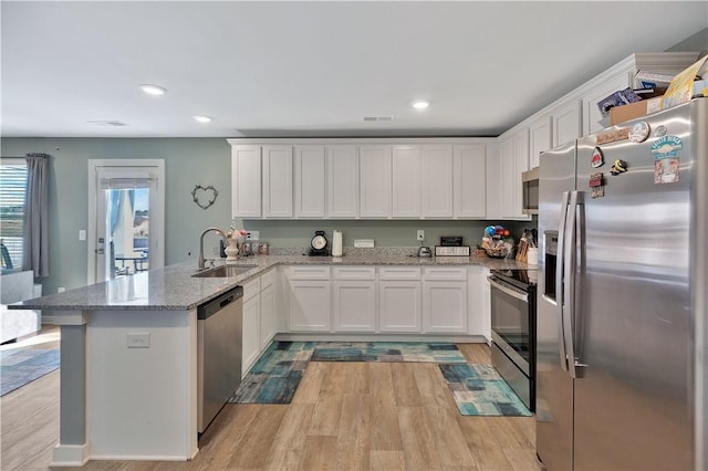 kitchen featuring kitchen peninsula, light hardwood / wood-style flooring, white cabinets, and stainless steel appliances