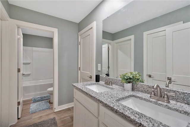 full bathroom with hardwood / wood-style flooring, vanity, toilet, and shower / washtub combination