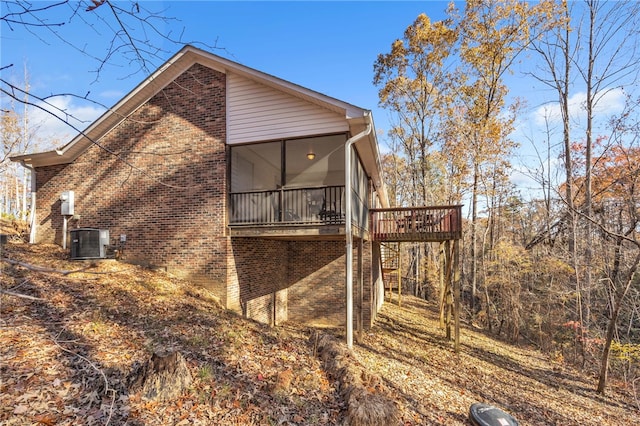 view of property exterior featuring a sunroom, cooling unit, and a deck