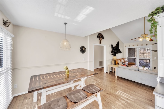 dining room featuring ceiling fan, vaulted ceiling, and light wood-type flooring