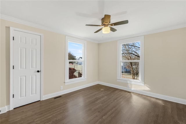 spare room with ornamental molding, dark wood-type flooring, ceiling fan, and a healthy amount of sunlight