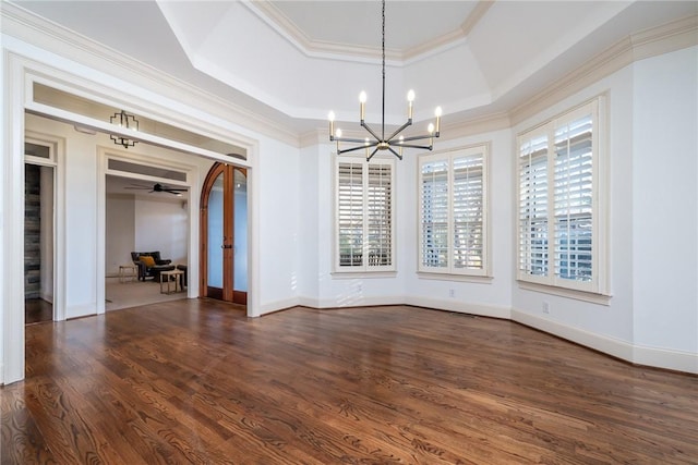 unfurnished dining area featuring a raised ceiling, ceiling fan with notable chandelier, dark hardwood / wood-style flooring, and crown molding