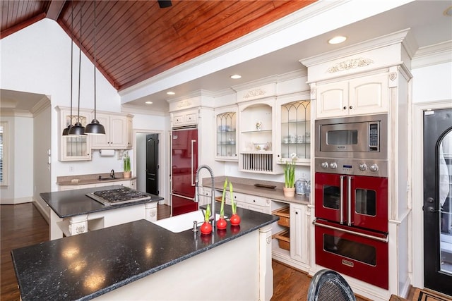 kitchen featuring dark hardwood / wood-style flooring, lofted ceiling with beams, built in appliances, pendant lighting, and a kitchen island with sink