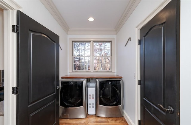 laundry area featuring washing machine and dryer, ornamental molding, and light wood-type flooring