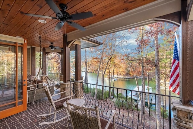 exterior space with ceiling fan, a balcony, and a water view