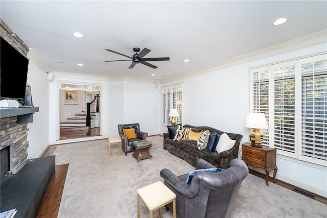 living room with ceiling fan, wood-type flooring, ornamental molding, and a fireplace