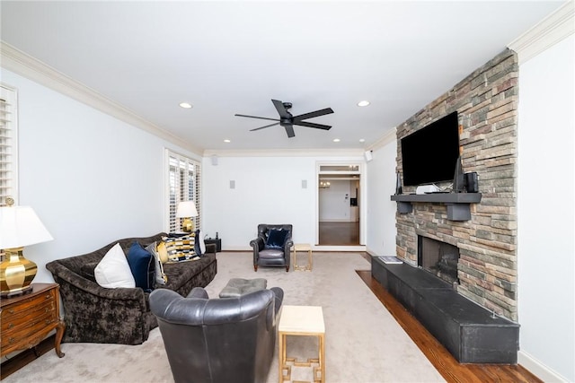 living room featuring ceiling fan, a fireplace, hardwood / wood-style floors, and ornamental molding