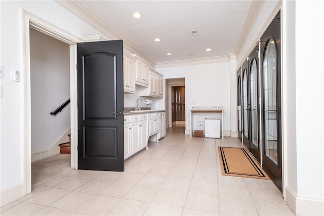 kitchen featuring light tile patterned floors, white cabinetry, crown molding, and sink