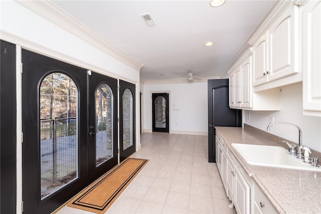 kitchen with ceiling fan, french doors, sink, white cabinets, and ornamental molding