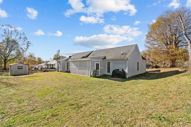 rear view of house featuring a yard and a storage unit