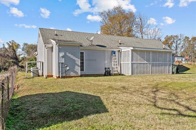 rear view of house featuring a lawn and central air condition unit