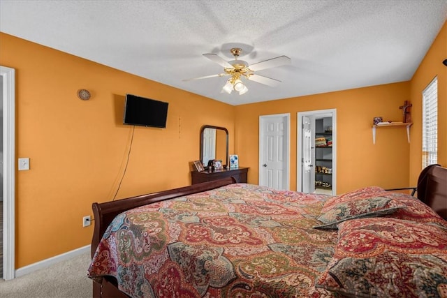 carpeted bedroom with ceiling fan and a textured ceiling