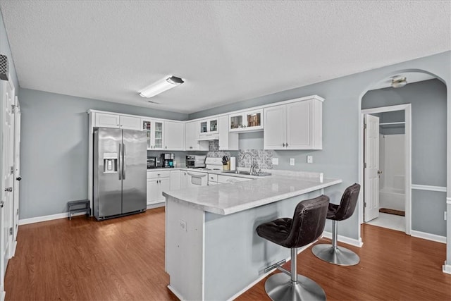 kitchen featuring sink, appliances with stainless steel finishes, white cabinetry, a kitchen bar, and kitchen peninsula